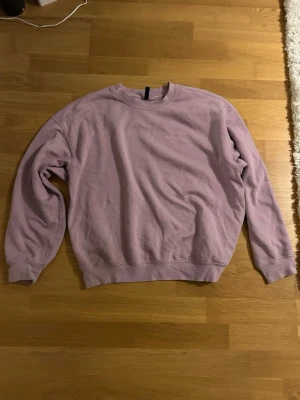 Ljuslila sweatshirt från H&M Divided - Sweatshirt i ljuslila från H&M Divided, storlek S. Klassisk rund hals och långa ärmar med ribbade muddar. Mjuk bomullskvalitet som är skön att ha på sig. Perfekt för chill dagar och enkel att matcha med jeans eller mjukisbyxor. Säljer då den ej används längre