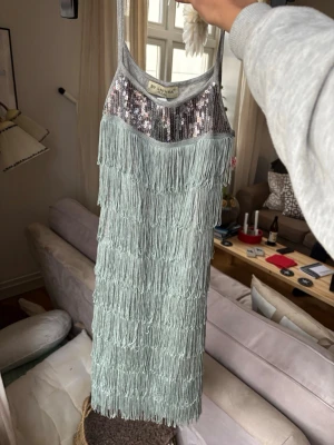 Klänning - Festklänning i storlek S med fransar. Superfin men aldrig använt så helt i nyskick. Grön framsida och grå baksida🩷