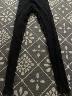 Svarta ribbade tights - Säljer ett par svarta ribbade tights från H&M Divided i storlek XS. De är stretchiga och har en tight passform med ribbad struktur. Högmidjade. Skriv gärna om ni har frågor🥰