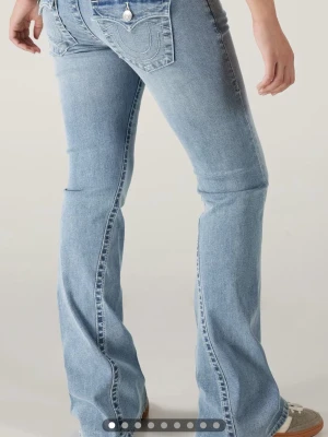  True Religion low jeans  - Snygga bootcut jeans i ljusblå tvätt från True Religion med klassiska fickor och tydliga sömmar bak. Jeansen har låg midja och är tillverkade i mjukt denim-material som ger en skön passform. Perfekta för dig som gillar retrovibbar och vill sticka ut. Pris går att diskutera, dom är uppsydda i benen så dom passar mig som är ungefär 155 lång 💕storlek 24