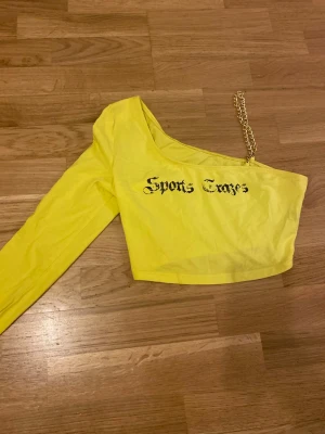 Gul oneshoulder topp  - Cool gul croppad topp från SHEIN med oneshoulder-design och lång ärm. Ena axeln har en snygg guldfärgad kedja istället för axelband som går att få bort även. Strl M men passar även S fint. Kanske blir den din nyårs topp🤩