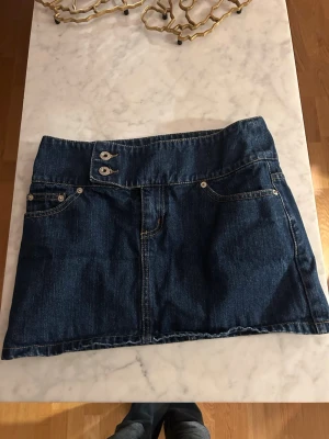 Mörkblå jeanskjol - Säljer en jätte snygg mörkblå jeanskjol. Kjolen dubbla knappar på sidan fram. Kjolen är i storlek 36.