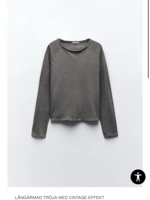 Grå långärmad tröja med vintage-look - Säljer en grå långärmad tröja från Zara med vintage-effekt. Tröjan har en rund halsringning och råa kanter vid nederkant och ärmslut som ger en avslappnad vibe. Perfekt för dig som gillar enkel och stilren design.