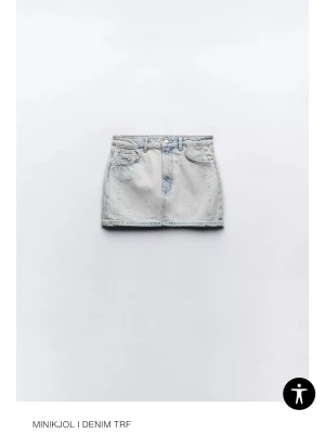 Ljusblå denim minikjol TRF - Säljer en ljusblå denim minikjol från TRF med klassisk femficksdesign och bälteshällor. Kjolen har en rak passform och stängs med knapp och dragkedja framtill. Perfekt att styla med sneakers eller boots.