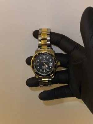 Guld och silver klocka - Bilderna visar en klocka i guld och silver med en svart urtavla. Perfekt för dig som vill ha en stilig och elegant look.