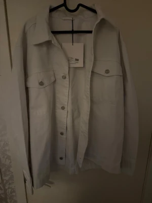 Vit overshirt från J.Lindeberg - Snygg vit overshirt från J.Lindeberg i storlek L. Jackans skick är helt ny och har aldrig använt säljs då den inte passade. Tveka inte att skriva vid frågor eller funderingar!