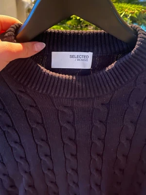 Mörkblå stickad tröja Selected Homme - Säljer en mörkblå stickad tröja från Selected Homme med snyggt kabelstickat mönster och ribbad rund hals. Passar M-S