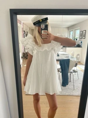 Vit plisserad kortklänning med volang - Så populär och eftertraktad klänning från Zara, så fin till studenten ❤️kontakta vid frågor annars är det bara att klicka på köp!! 