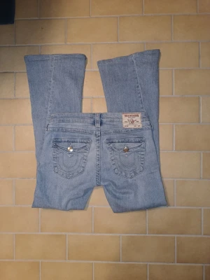 True Religion lågmidjade/lowwaist ljusblå flared bootcut jeans - Superfina True Religion jeans i ljusblå tvätt. Low waist/lågmidjad modell med perfekt passform. Storlek XS (26). Jättebra skick, endast en mycket liten fläck som knappt syns och som går bort i tvätten. Väldigt trendiga och svåra att hitta. Pris kan diskuteras vid seriöst intresse..