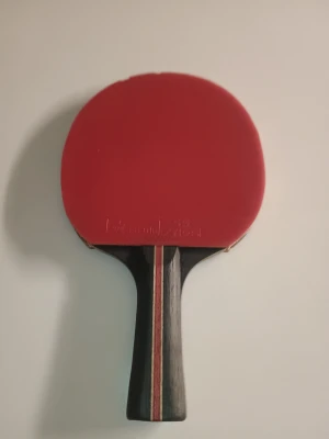 Stiga 5 Star pingisracket - Pingisracket från Stiga med röd beläggning på ena sidan och svart på andra. Handtaget har en svart bas med röda och vita ränder. Perfekt för dig som vill ta ditt bordtennisspel till nästa nivå.