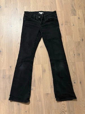 Svarta bootcut jeans med fickdetaljer - Snygga svarta jeans med bootcut passform och klassiska fem fickor. Bakfickorna är fint dekorerade. Säljer för de blivit för små men det är inga konstigheter på dem alls!
