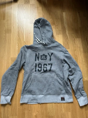 Polo Ralph Lauren hoodie  - Riktigt fet polo Ralph lauren hoodie i grå med svart text, storlek M, riktigt bra skick, lite peeling på texten men borde vara okej👌 skriv gärna vid frågor! 