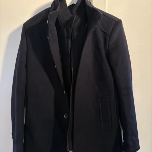 Mörkblå ullrock med dragkedja - Stilren mörkblå rock, storlek M. Aldrig använd. Nypris 1900kr!