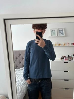 Blå långärmad tröja från GANT - Snygg blå långärmad tröja från Gant med rund halsringning och diskret logga broderad på bröstet. Tillverkad i mjukt bomullsmaterial som känns skönt mot huden. Perfekt för en avslappnad och stilren look. Strl: S