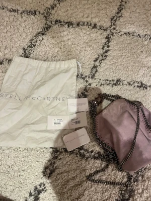 Ljuslila axelväska Stella McCartney - Säljer en snygg ljuslila axelväska från Stella McCartney ny pris 11099. Har lite defekter på kedjan och i väskan men inget som gör att den inte går att använda 