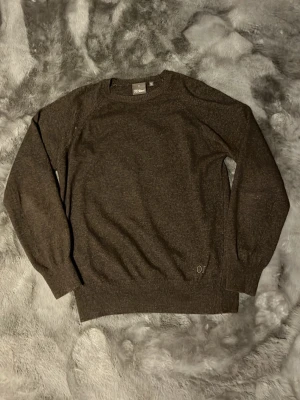 Oscar Jacobsson merino - Mjuk brun stickad merinoull tröja från oscar Jacobsson med rund halsringning och diskret OJ-broderi nertill. Tröjan har långa ärmar och ribbade muddar vid ärmslut och nederkant. Perfekt för lager-på-lager och enkel att matcha.