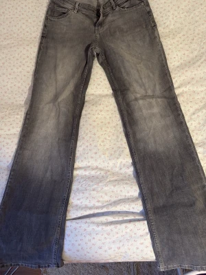 Grå raka jeans med slitningar och lågmidjade! - Snygga grå jeans med raka ben och diskreta slitningar framtill. Klassisk femficksmodell med normal passform och ljus tvätt. Perfekta till en avslappnad stil och funkar året runt.