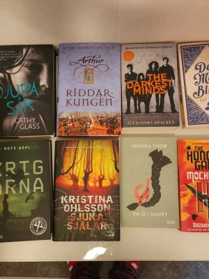 Blandade ungdomsromaner och fantasy - Paket med åtta skönlitterära böcker, bland annat 'Djupa sår', 'Riddarkungen', 'The Darkest Minds', 'De mörka blommorna', 'Krigarna', 'Sjuka själar', 'En ö i havet' och 'Hungerspelen: Mockingjay'. Omslagen är färgstarka och varierar mellan svart, blått, orange och grönt. Perfekt för dig som gillar spänning, äventyr och fantasy. För en book är det 70 till 100kr.