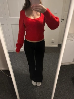 Röd stickad tröja från H&M - Trendig röd stickad tröja från H&M med fyrkantig ringning och långa ärmar. Tröjan är ribbstickad och har en croppad passform som passar perfekt till höga byxor. Perfekt för dig som vill ha en färgklick i garderoben.