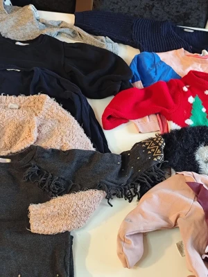 Mix av stickade och fleece tröjor stl 110/116 - Flera olika tröjor i mörka och ljusa färger, bland annat stickade och fleecevarianter. Några har fransdetaljer, paljetter och julmönster. Perfekt för dig som vill ha variation i garderoben och gillar både klassiska och lekfulla stilar. Du är varmt välkommen att kika på mina andra annonser.