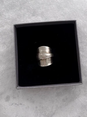 Bred ring i äkta silver tillverkad på återvunna silverbestick - Unik och chunky ring i äkta silver. Ringen har en bred, rundad form med en markerad kant som ger en cool och edgy look. Perfekt för dig som gillar statement-smycken och vill sticka ut.