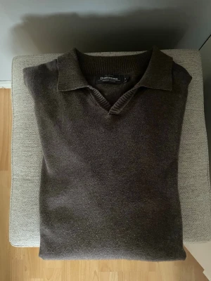 Brun stickad tröja med krage - Snygg brun stickad tröja från Dressmann med klassisk krage och v-ringning. Tröjan har långa ärmar och ribbade muddar vid ärmslut och nederkant. Perfekt för dig som gillar en stilren och enkel look. Priset kan diskuteras 