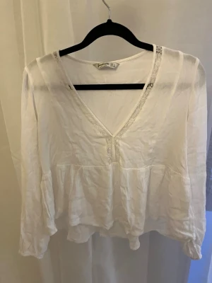 Vit blus med v-ringning och spetsdetalj - Vit blus med v-ringning och tunna spetsdetaljer längs halsen