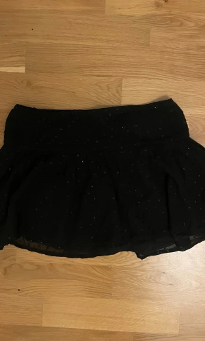 Svart glittrig volangkjol - Superfin glittrig volangkjol från Young Guns i storlek 158/164. Knappt använd. Säljer tröjan från samma sett också. Skriv om du har några frågor!🩷