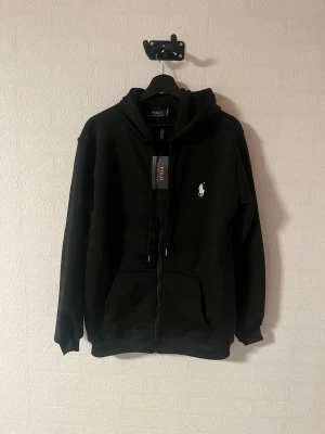 Ralph Lauren Hoodie - Svart Ralph Lauren hoodie i storlek Medium, helt ny med prislapp kvar. Aldrig använd. Klassisk modell. Skriv vid frågor, jag svarar snabbt!