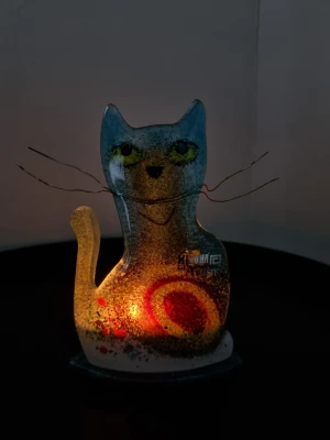 Glaskatt ljuslykta från Grekland - Unik glaskatt i blått, rött och gult med färgglada detaljer och koppartråd som morrhår. Katten står på en blå bas med plats för värmeljus. Perfekt som dekoration i hemmet för dig som gillar konstnärliga prydnader.