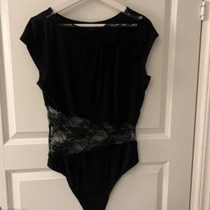Svart body med spetsdetaljer - Snygg svart body med spets. Storlek L. Köpt på vinted så vet tyvärr inte vart den är ifrån men gissar på hm eller SHEIN. 