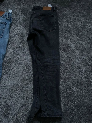 Svarta Levi's 502 jeans - Svarta jeans från Levi's modell 502 med klassisk femficksdesign och rak passform. Jeansen har en brun läderpatch bak i midjan och subtila sömmar. Perfekta för en stilren och avslappnad look.