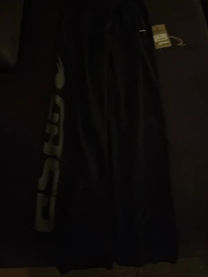 Svarta sweatpants från GASP - Svarta sweatpants från GASP med stort tryck längs benet. Perfekta för träning eller chill, med bekväm passform och elastisk midja. Klassisk sportig look och mjukt material.