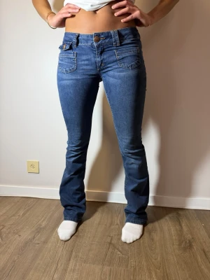Blå bootcut jeans från ONLY - Säljer ett par klassiska blå bootcut jeans från ONLY med snygga kontrastsömmar och fem fickor. Jeansen har låg midja och är tillverkade i stretchigt denim för en bekväm passform. Perfekta för en avslappnad och trendig look.