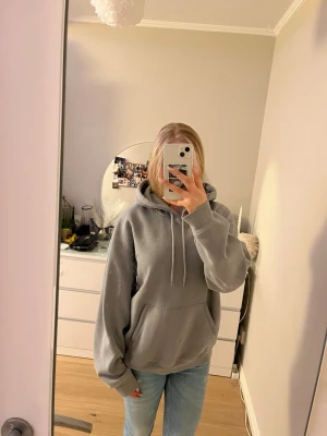 Grå/blå oversized hoodie med huva - Säljer en grå/blå oversized hoodie från H&M med stor känguruficka framtill och justerbar dragsko i huvan. Hoodien har långa ärmar och ribbade muddar vid ärmslut och nederkant. Perfekt för en chill och avslappnad stil. Den är i storlek L då jag ville ha en oversized känsla. 