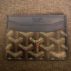 Goy4rd korthållare - Snygg korthållare från Goy4rd i blått skinn med klassiskt mönster i brunt, vitt och gult. Insidan är fodrad i gult och har flera fack för kort. Perfekt accessoar för dig som vill ha något stilrent och lyxigt i fickan.
