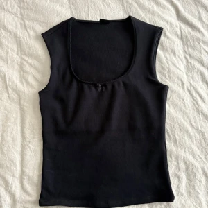 Topp från Gina tricot  - Söt svart topp med u-ring med en liten rosett framtill. Aldrig använd då den är för stor. Storlek M