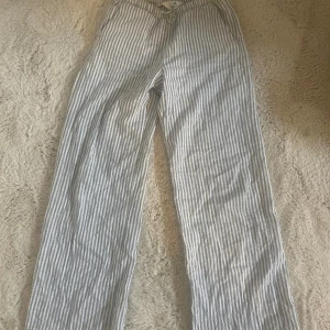 Randiga linnebyxor med snörning från hm - Snygga linnebyxor med blå och vita ränder, perfekt för en chill och avslappnad stil. Byxorna har rak passform och snörning i midjan för extra komfort. Luftigt material som passar bra när det är varmt ute.