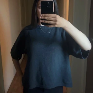 Mörkblå/grön stickad tröja från 157 - Mysig mörkgrön stickad tröja från 157 med avslappnad passform och trekvartsärm. Tröjan har rund halsringning med ribbad kant och är perfekt för lager-på-lager-stil. Enkel och stilren design som funkar till många outfits.