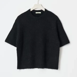 Svart stickad tröja från Gina Tricot - Svart stickad tröja från Gina Tricot med kort ärm och rund halsringning. Tröjan har en loose passform och är gjord i ett mjukt, fluffigt material som känns riktigt mysigt. Perfekt att styla med jeans eller kjol för en chill look.