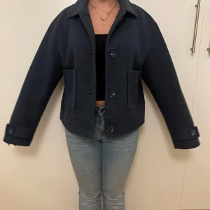 Mörkblå kappa - Snygg mörkblå kappa krage, stora knappar framtill och två rejäla fickor. Jackan har en lite oversized passform och långa ärmar med knappdetalj vid mudden. Perfekt för dig som gillar stilren och enkel design 💓💓Använd ett fåtal gånger! 😙