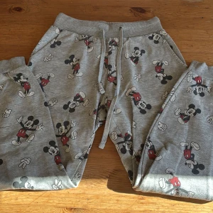 Grå Disney Mickey Mouse mjukisbyxor XS - Grå mjukisbyxor från Disney med all-over print av Mickey Mouse i svart, vitt och rött.
