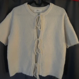 Vit kofta med knyt från Gina Tricot - Kortärmad vit stickad kofta från Gina Tricot med knyte framtil. Tröjan är i storlek XS och är jätte fin och perfekt till hösten. Helt slutsåld, säljs för att den inte kommer till användning. Kontakta för egna bilder.