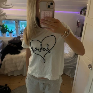 Vit t-shirt med hjärta från Vero Moda - Vit t-shirt från Vero Moda. Jag har använt den typ två gånger, men jag tycker inte den passar mig så bra längre💞Jag skulle nog säga att den är lite stor i storlek så känns mer som S