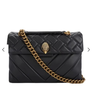 Svart Kurt Geiger väska - Snygg svart stor axelväska från Kurt Geiger i quiltat skinn med guldig kedja och ikonisk örndekor på locket. Väskan har väldigt små slitningar på baksidan men annars inget❤️nypris 3600kr