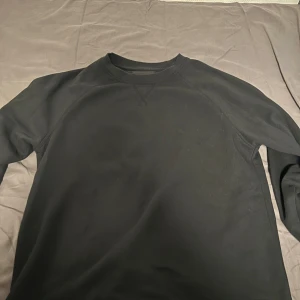 Svart sweatshirt från 157, strl M - En stilren svart sweatshirt från 157 i storlek M. Tröjan har rund halsringning, långa ärmar och är gjord i mjuk bomull. Perfekt för en chill och enkel look. Klassisk design utan tryck eller mönster. Knappt använd, inga defekter eller sådant.