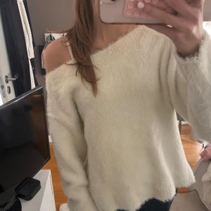 Offshoulder fluffig vit tröja H&M - Supermjuk och fluffig vit tröja från H&M med offshoulder-design. Tröjan har lång ärm och en loose passform, perfekt för dig som gillar en avslappnad och trendig stil. Materialet är mysigt och ger en lyxig känsla.