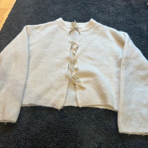 Vit kofta med knyt från Gina Tricot - Superfin vit stickad kofta från Gina Tricot med snygga knytband framtill. Koftan har lång ärm, rund halsringning och är croppad i modellen. Är storlek 170 men passar S också💗