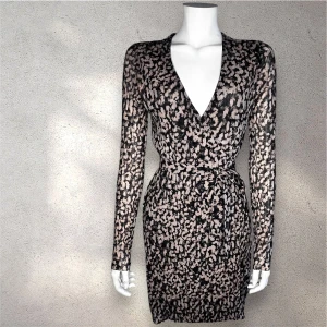 klänning med mönster från & Other Stories - Snygg kort klänning  från & Other Stories med svart och beige blommigt mönster. Klänningen har lång ärm, v-ringad hals och knyt i midjan för en smickrande siluett. Materialet är lätt och följsamt, perfekt för dig som gillar en feminin och trendig look. #&otherstories 