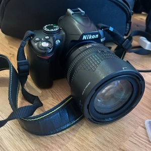 Nikon D3000 + 18-105mm F3.5-5.6G AF-S ED - Perfekt för både nybörjare och entusiastfotografer. Ingår: - Nikon D3000 - Nikon 18-105mm F3.5-5.6G AF-S ED - Nikon Camera Bag - Transcend USB 3.1 Multi-uuCard Reader - Nikon Quick Charger MH-23 - San Disk Ultra 32GB 120 MB/s  - Kamerarem - Hoya Pro 1 Digital Filter